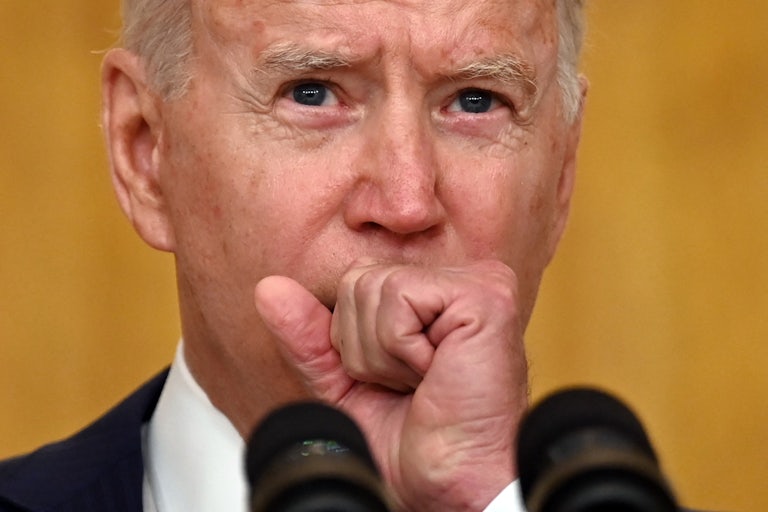 A close-up of President Joe Biden clasping his fist to his mouth.