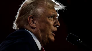 Donald Trump in profile speaking vehemently into a microphone