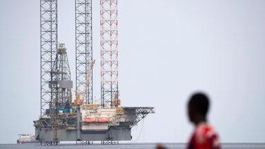 A person looks at an off-shore oil rig.