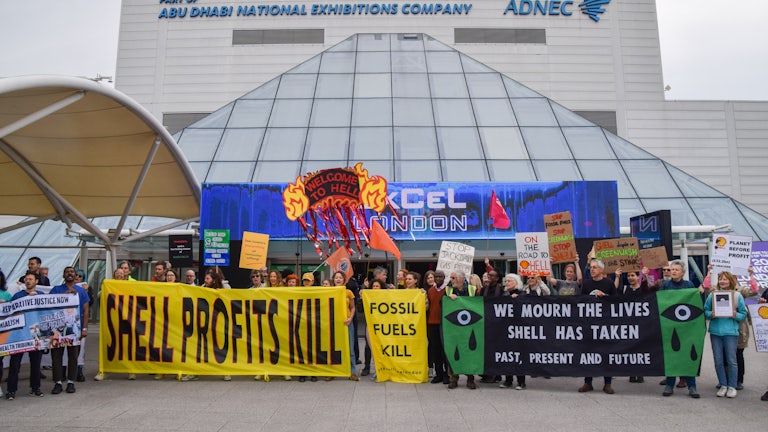 Protesters hold signs reading "Shell Profits Kill" and "We Mourn the Lives Shell Has Taken."