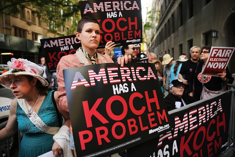 Protesters hold signs that read "America has a Koch problem"