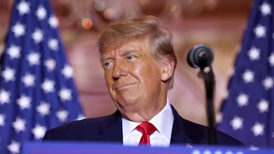 Donald Trump stands at a lectern and smiles