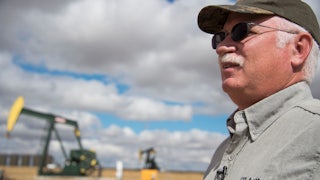 An oil industry consultant talks in front of a drilling rig.