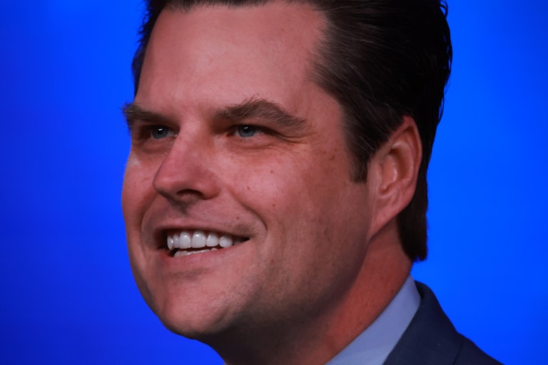 close-up of Matt Gaetz smiling with blue background (looks a bit like a creepy yearbook photo)