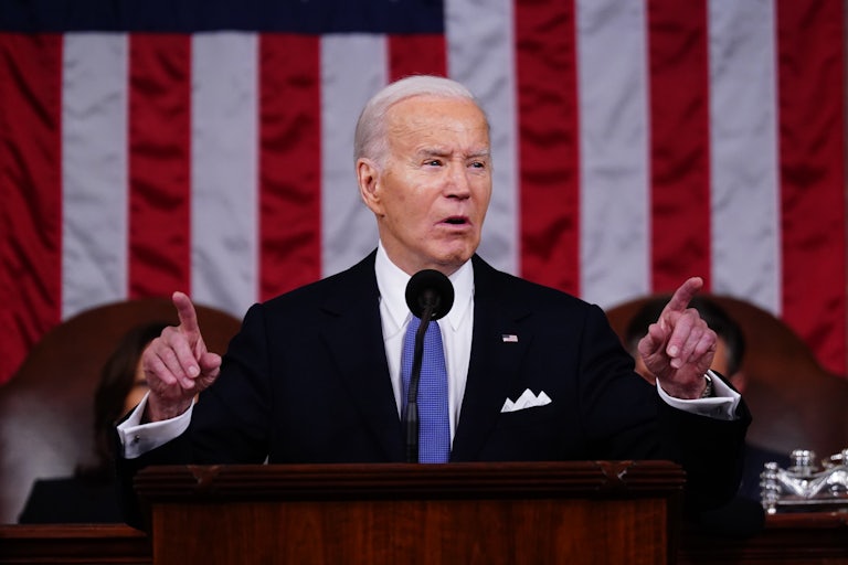Joe Biden speaks during the State of the Union and points both index fingers outwards and up