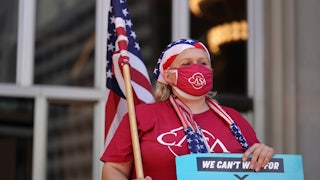 A demonstrator draped in American flag iconography holds a "climate justice" sign.