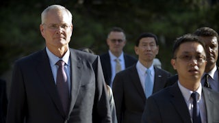 Exxon Mobil CEO Darren Woods walks with several other people.