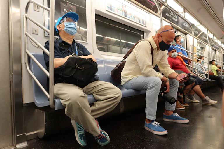People wear face masks while riding the New York City subway
