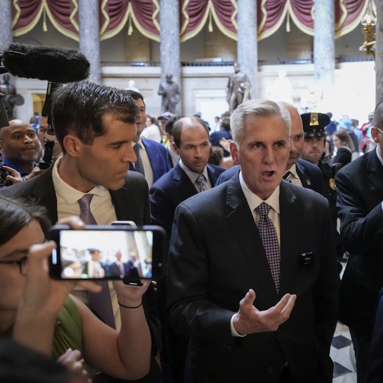 Kevin McCarthy talks while walking, surrounded by other people.
