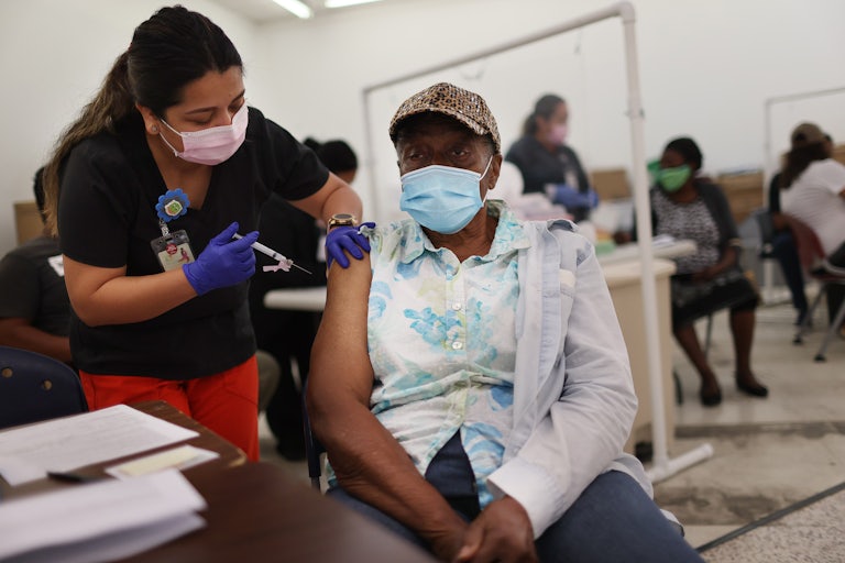 A nurse administers a Moderna COVID-19 vaccine to a masked patient at a clinic in Florida.