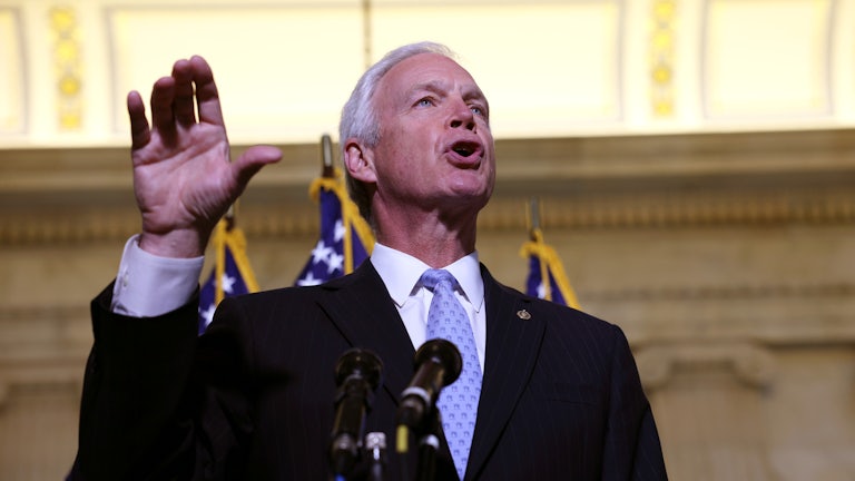 Senator Ron Johnson raises his hand while addressing reporters at a press conference on Capitol Hill