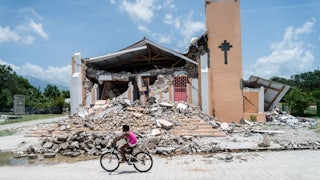 A child rides a bicycle in front of a church demolished by an earthquake in Chardonnières, Haiti.