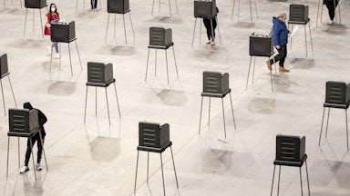 A few people stand amid a mass of empty polling booths.