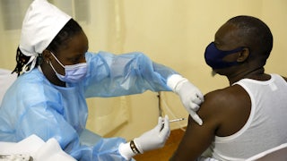 A medical worker injects a shot into a patient's left arm.