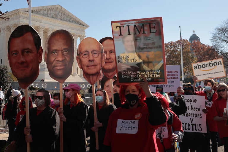 Demonstrators carry large cut-outs of the heads of the Supreme Court's justices during a protest.