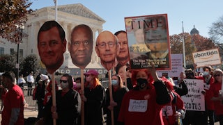 Demonstrators carry large cut-outs of the heads of the Supreme Court's justices during a protest.