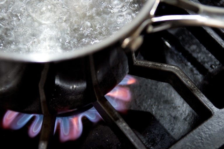 A pot with boiling water sits on a gas burner.