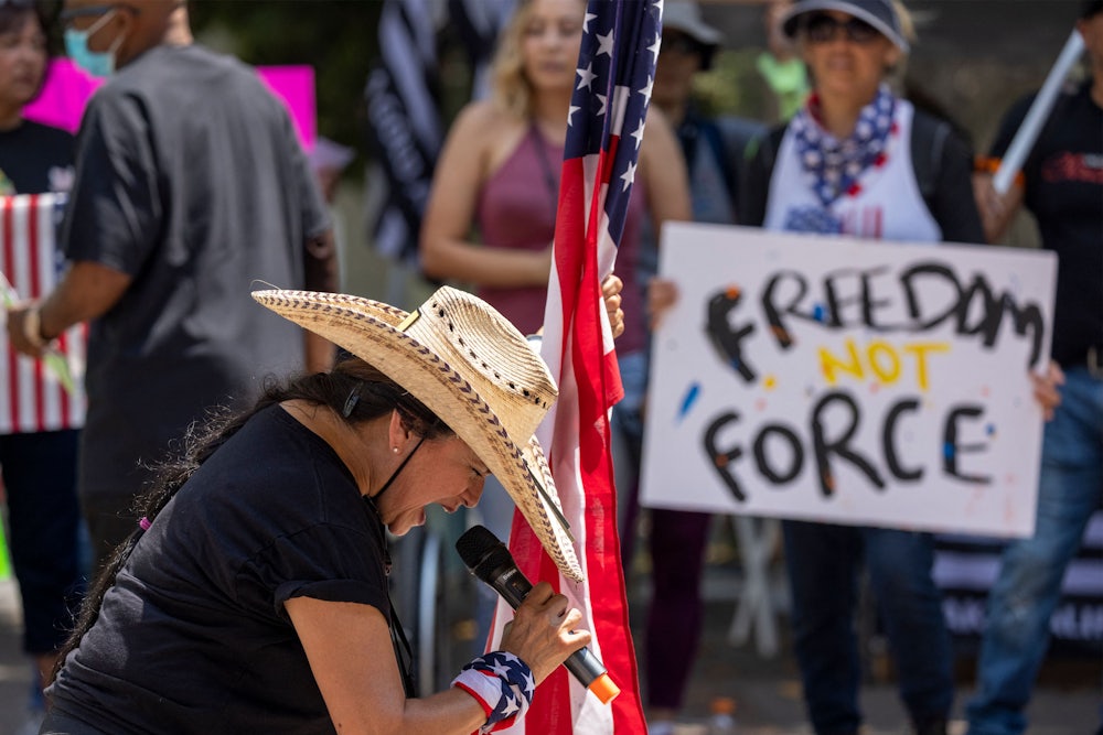 A woman holds an American flag and prays at an anti-vaccine rally in Los Angeles.