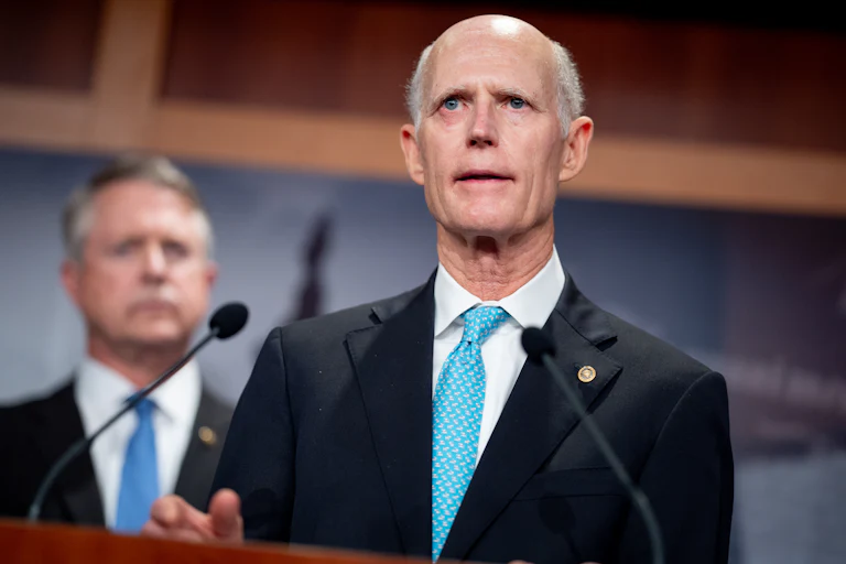 Senator Rick Scott speaking at a lecturn (he looks weird)