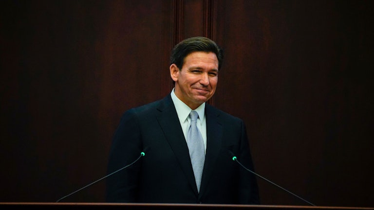 Florida Governor Ron DeSantis smiles at a podium