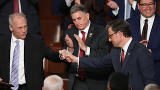 Mike Johnson shakes hands with Steve Scalise, surrounded by clapping colleagues.