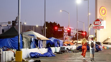 People walk past a homeless encampment near a Target store in Los Angeles, California. 