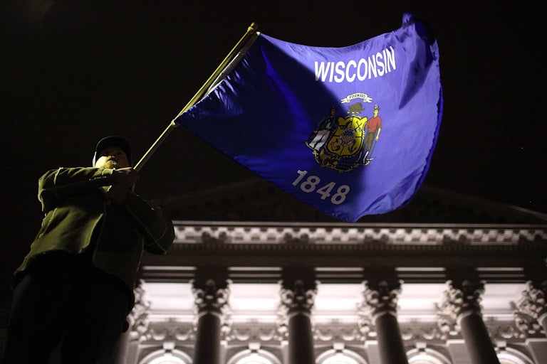 A man waves the Wisconsin state flag on the steps of the state capitol in Madison.