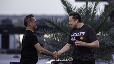 T-Mobile CEO Mike Sievert shakes the hand of Tesla's Elon Musk at an event in Boca Chica Beach, Texas.