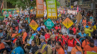 Activists holding brightly colored signs, including those reading "livable future for all of us" and "fossil fuels kill."