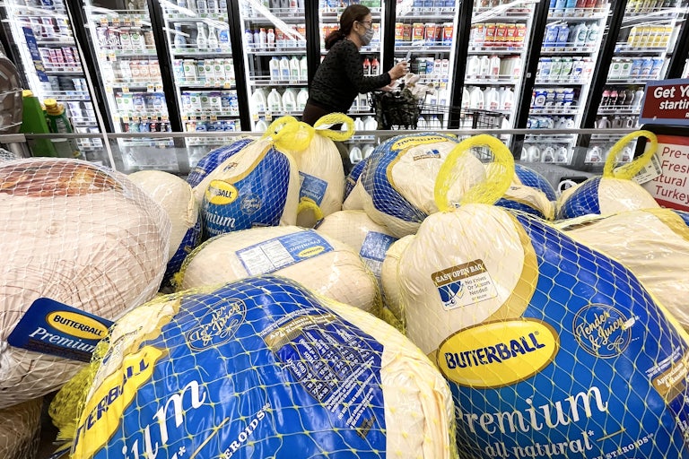 A shopper walks past turkeys displayed for sale in a grocery store ahead of the Thanksgiving holiday.