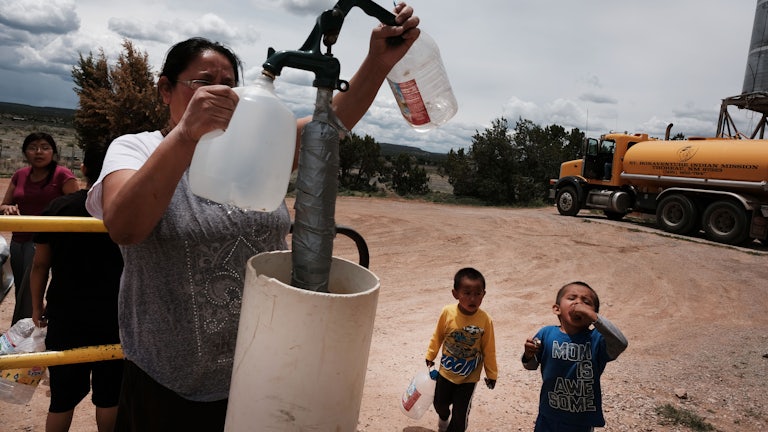 A woman fills water jugs at a public tap.