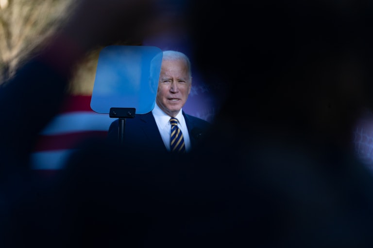 President Biden looks at a teleprompter while addressing a crowd.