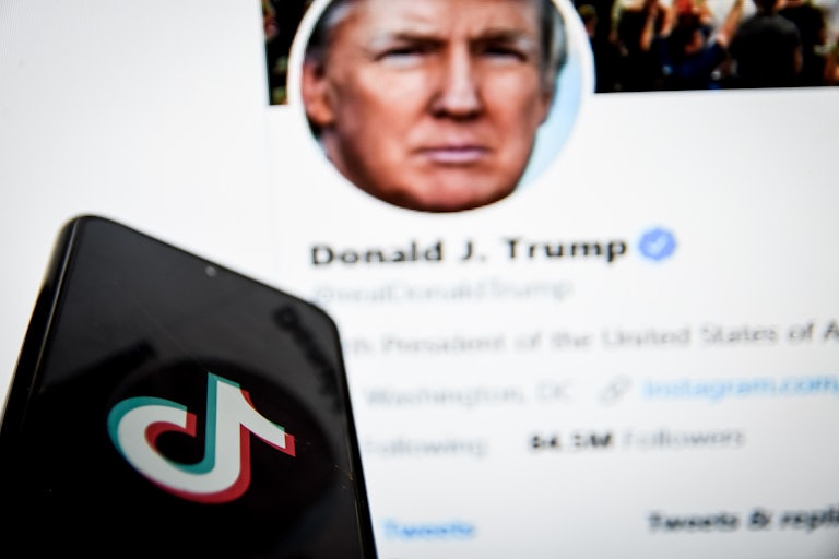 A phone with the TikTok logo held in front of Trump's Twitter feed
