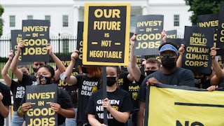 Climate activists hold signs in front of the White House.