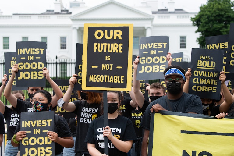 Climate activists hold signs in front of the White House.