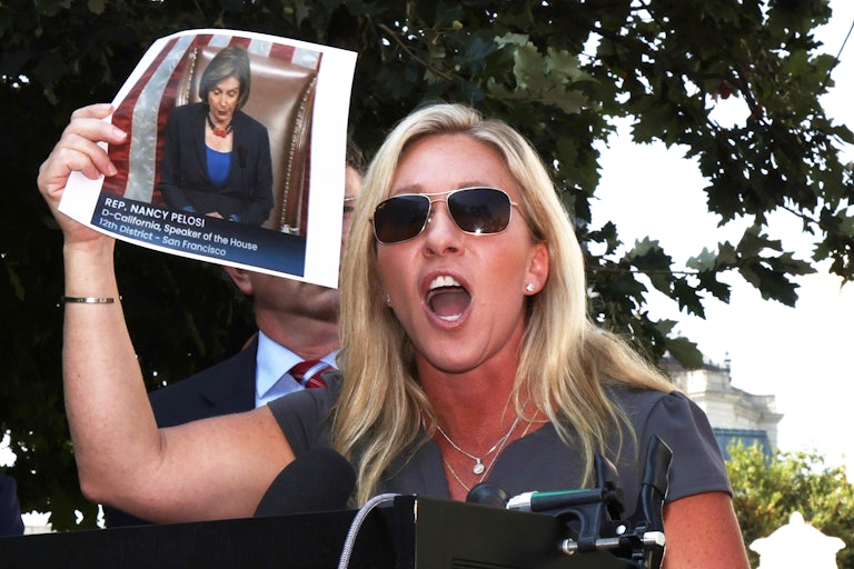 Marjorie Taylor Greene holds up a picture of Nancy Pelosi as she bellows complaints about having to wear a mask.
