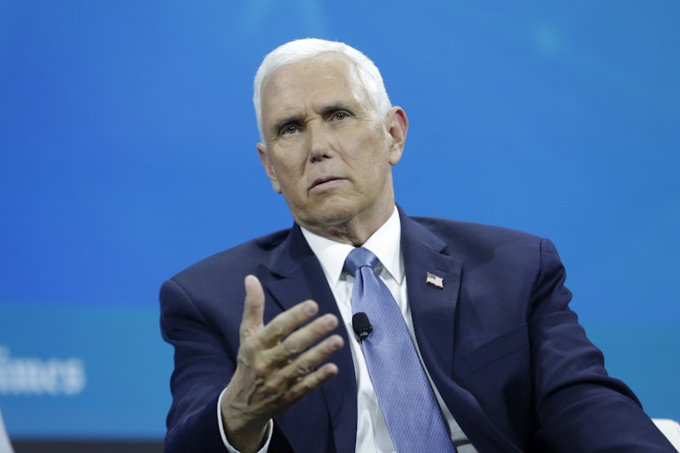 Mike Pence sitting in front of a blue background, talking and making a hand gesture