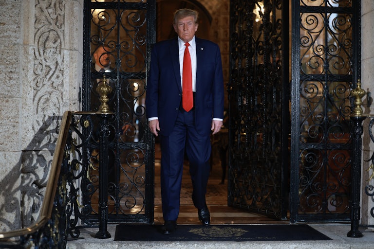 Donald Trump walks out of a door with a lot of intricate ironwork