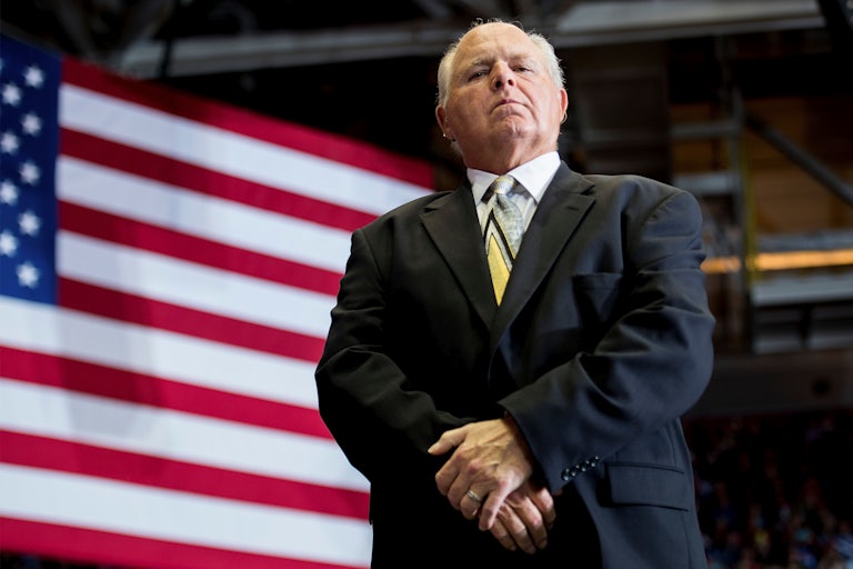 Rush Limbaugh, seen from below, standing in front of an American flag.