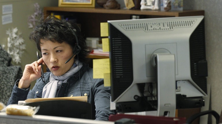 a woman with a headset and a computer monitor at a mental health call center