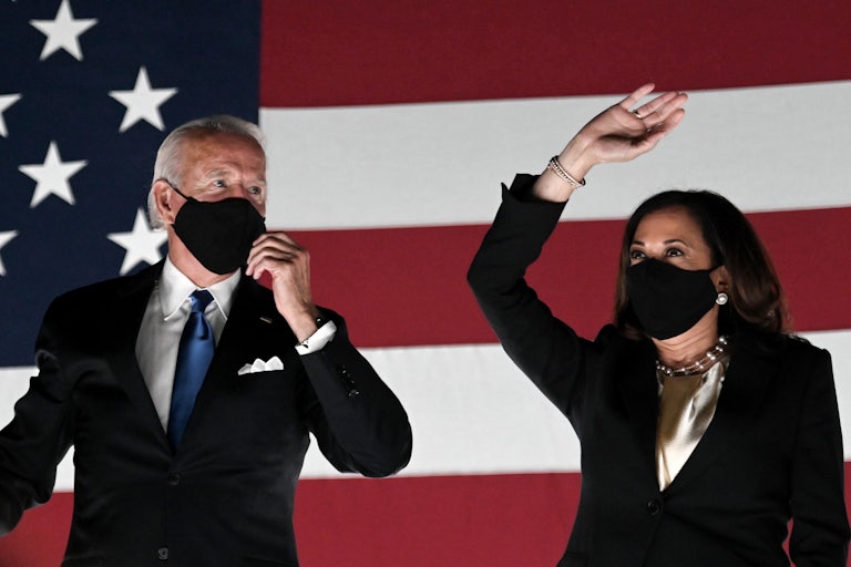 Joe Biden and Kamala Harris stand in front of an American flag backdrop
