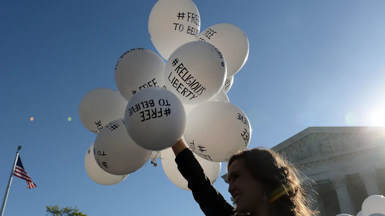 A protester holds balloons calling for religious freedom outside the Supreme Court.