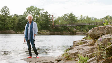 Elizabeth Strout stands in front of the Androscoggin River in Topsham, Maine in 2022