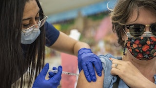 A woman receives her second Moderna COVID-19 vaccine at a vaccination site at a senior center in San Antonio, Texas