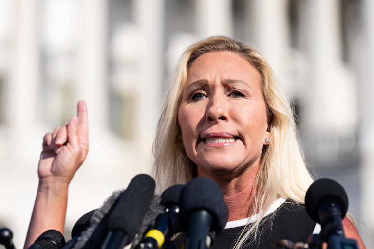 Marjorie Taylor Greene gestures as she speaks into microphones