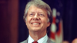 Jimmy Carter, running for reelection, smiles a big toothy grin in front of an American flag.
