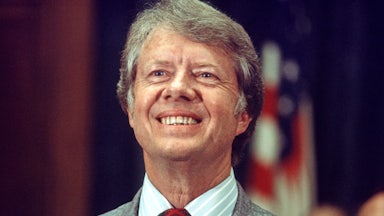 Jimmy Carter, running for reelection, smiles a big toothy grin in front of an American flag.