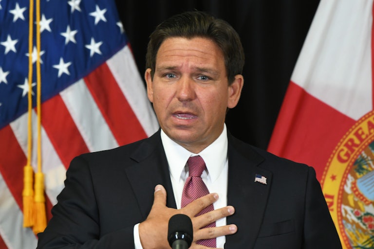 Ron DeSantis holds his hand to his chest as he speaks into a microphone