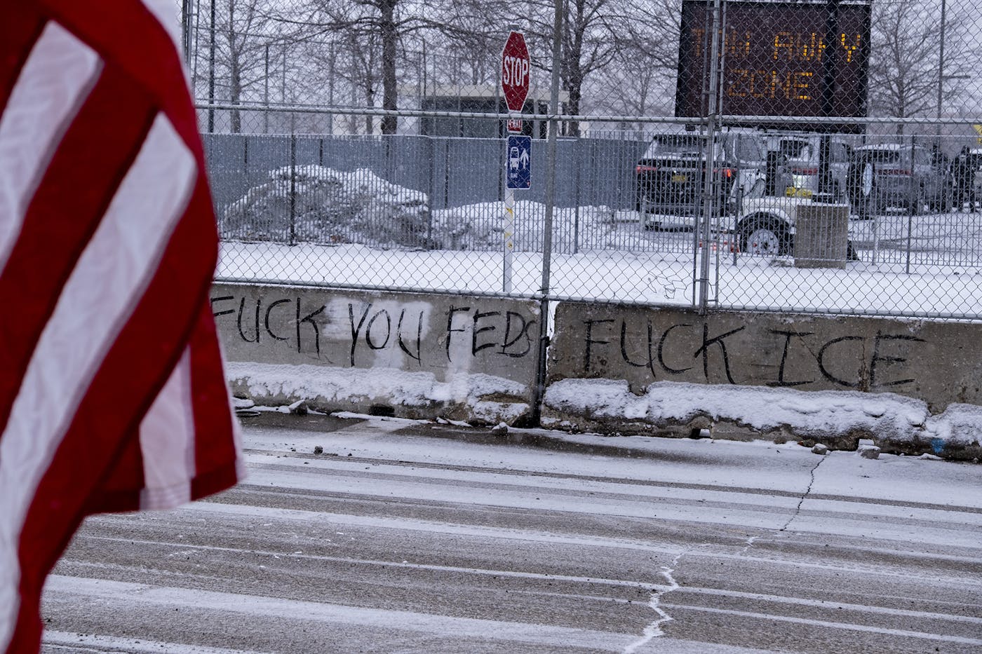 Graffiti on a concrete ledge next to a sidewalk reads "FUCK YOU FED, FUCK ICE"