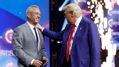 Trump pats RFK Jr. on the shoulder as the latter smiles.